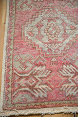 Hand-knotted Vintage Distressed Oushak rug corner, showing worn blush pink pile, selvage, and fringe.