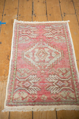Distressed corner of vintage Oushak rug with blush pink potted plant motif and fringe.