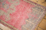 Distressed Oushak rug close-up: low pile, pink, time-softened silver, and tangerine motifs.