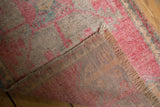 Distressed pink and silver Oushak rug's hand-knotted back, woven fringe, and low pile.
