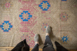 Textured Distressed Jijim carpet with geometric blue and blush raspberry stylized flowers.