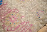 Distressed vintage Jijim carpet's textured weave with abrashes, showing geometric blush raspberry patterns.