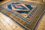 Stepped apricot medallion with intricate outlining on a dark navy blue vintage Oushak carpet.