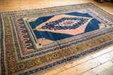 Intricate bronze, navy, and ivory borders with stepped apricot medallion on vintage Oushak rug corner.
