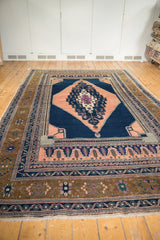 Vintage Oushak rug's intricate dark navy and apricot medallion with bronze outer border.