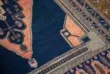 Intricate apricot stepped outlining on a dark navy field of a vintage Oushak rug.