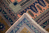 Folded corner of vintage Oushak carpet, showing intricate apricot, navy, and bronze patterns with original selvage.