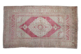 Vintage distressed Oushak rug, faded red medallion, beige abrashed field and corner spandrels.