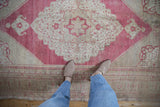 Distressed vintage Oushak rug, showing abrashed raspberry and beige pile texture.