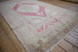 Distressed Oushak rug, angled view showing low pile and abrashed faded raspberry and ivory.