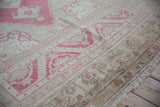 Distressed vintage Oushak rug detail, blush geometric motifs, and low, even pile.