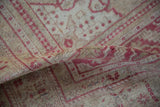 Distressed low pile of the Oushak rug, highlighting faded raspberry and sand patterns.