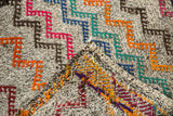 Folded vintage Jijim carpet corner, revealing hand-woven texture and multicolored zigzag design.