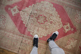 Overhead view showing the low pile and distressed medallion of a vintage Oushak carpet.