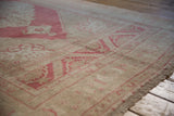 Low pile texture and raspberry red chevron border of a vintage distressed Oushak rug.
