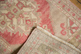 Distressed Oushak rug corner showing low pile, ivory fringe, and hand-knotted foundation.