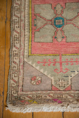 Distressed Oushak rug's corner with original selvage, geometric border, and fringe detail.
