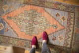 Distressed Oushak runner showcasing central germinating plant medallion with apricot, ivory, and blue abrash.