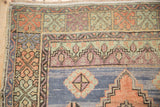 Vintage distressed Oushak rug showing even wear across blue and apricot geometric motifs.