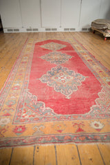 Distressed cherry red vintage Oushak rug, showing scalloped oxidized silver medallion and saffron plant border.