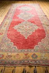 Distressed Oushak runner featuring triple Rococo-inspired medallions, cherry red abrashes, and a saffron plant border.