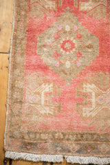 Distressed Oushak rug corner featuring faded raspberry, bronze motifs, and visible fringe.