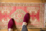 Distressed vintage Oushak rug mat with soft raspberry and faded bronze colors.