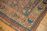 Antique Caucasian rug corner: geometric terra cotta, sky blue borders, and light tatter.