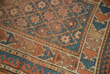 Antique Caucasian rug corner showing geometric trellis, star motifs, sky blue, and terra cotta patinaed pile.