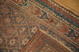 Antique Caucasian rug showing its hand-knotted foundation, geometric border, and light tatter.