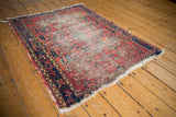 Vintage Lilihan rug corner with worn red pile, detailed navy border, and tattered fringe.