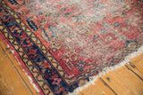 Corner detail of vintage Lilihan rug, with worn red field and contrasting navy, gold borders.