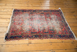 Close-up of vintage Lilihan rug corner, revealing worn cherry red field and tattered fringe.