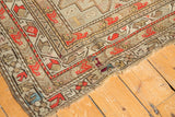 Antique Caucasian rug corner with brick red geometrics, wear to knot heads, and border patch.