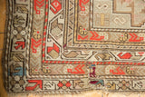 Antique Caucasian rug's geometric border with brick red tones and a visible patch.