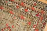 Geometric border design with storied wear on an antique Caucasian rug, brick red and silver-brown.