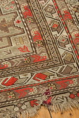 Visible geometric border, rust motifs, and fringe with a threadbare area on an antique Caucasian rug.