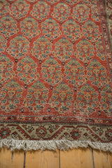 Vintage Hamadan rug corner displaying brick red allover boteh, meandering border, and fringe.