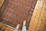 Vintage Hamadan rug corner, brick red boteh field, antique ivory vine border, and visible wear.