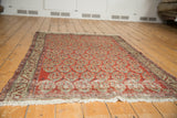 Fringed end of vintage Persian Hamadan rug showing worn pile and visible foundation.