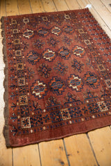 Corner detail of repeating gul motifs, dark navy blue, and secure chestnut brown side.