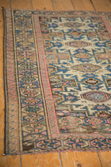 Vintage Caucasian rug with geometric multi-medallion border, pinwheel motifs, and time-softened cobalt blue and blush tones.