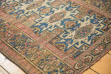 Geometric motifs and multi-medallions in blush, cobalt blue, and beige on a vintage Caucasian rug corner.