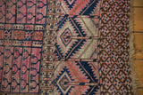 Antique Turkmen rug's side view with geometric tent cover motifs and fringed edge.
