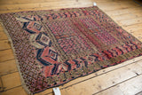 Geometric fuchsia and navy borders on an antique Turkmen rug's secure edge, with visible wear.