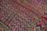 Fuchsia, navy, and ivory tent cover motif with visible wear on antique Turkmen rug.