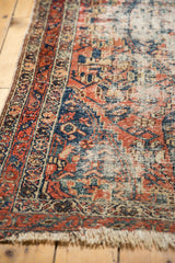 Antique Malayer rug's hand-knotted border and worn fringe, faded cherry and indigo hues.