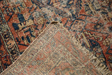 Antique Malayer rug's worn cherry red, navy pile and hand-knotted foundation with tattered fringe.