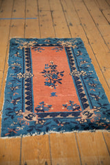 Early 20th century Chinese Peking rug corner, apricot field, indigo floral border, tattered ends.