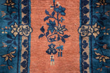 Apricot field with indigo floral vine and wide cobalt blue border on a Peking rug.